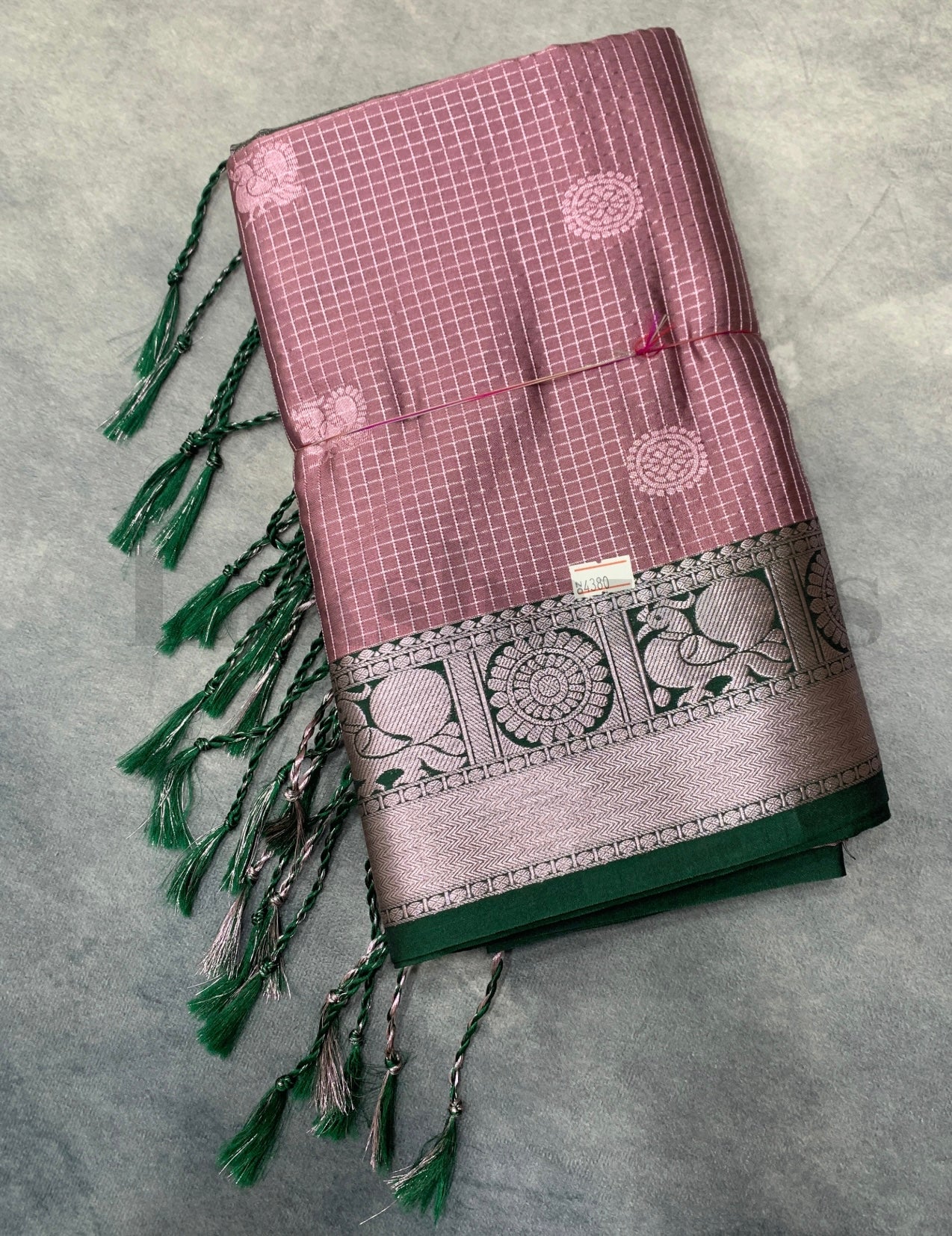 Decorative fabric with intricate patterns and tassels on a gray background